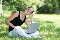 Junge Frau mit Notebook auf einer Wiese